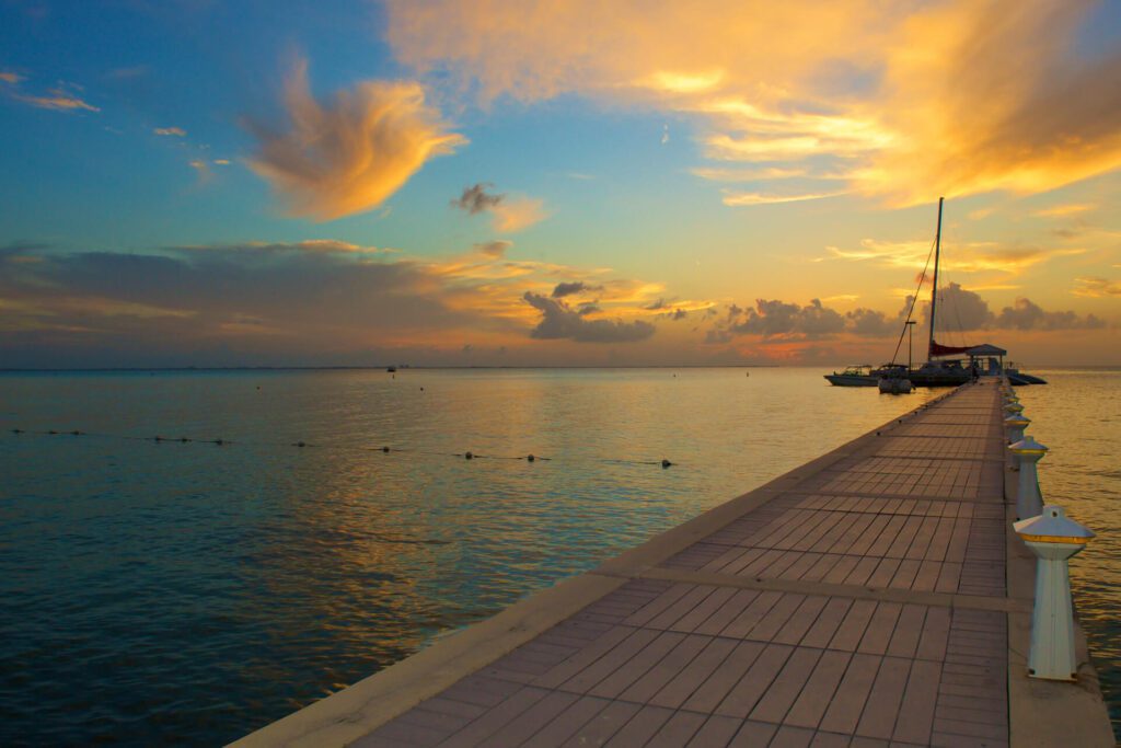 A catamaran at the end of a dock at sunset