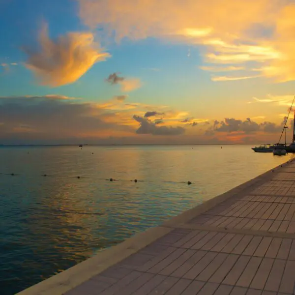 A catamaran at the end of a dock at sunset