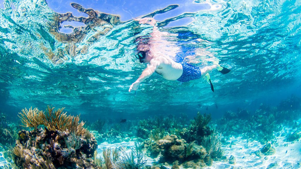 man snorkelling by coral reef