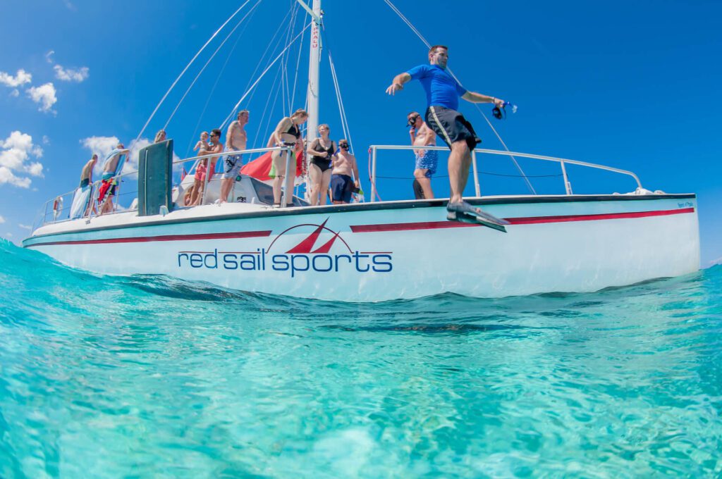 Snorkelers jumping from a catamaran in Grand Cayman with Red Sail Sports