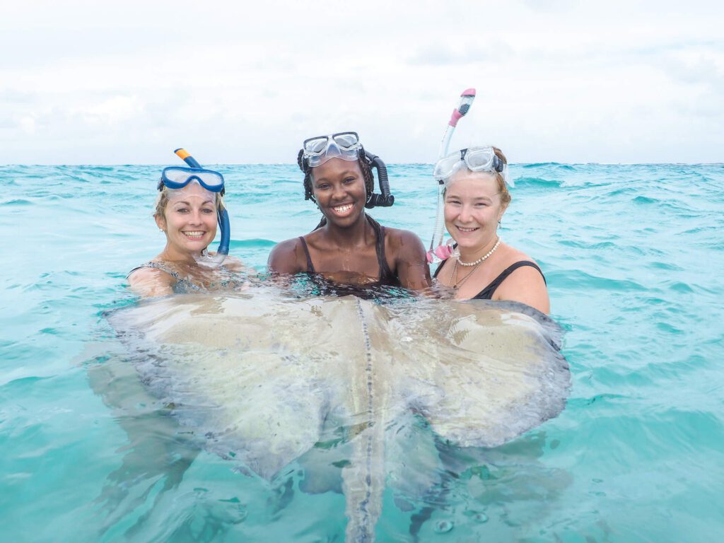 3 woman swimming with stingray