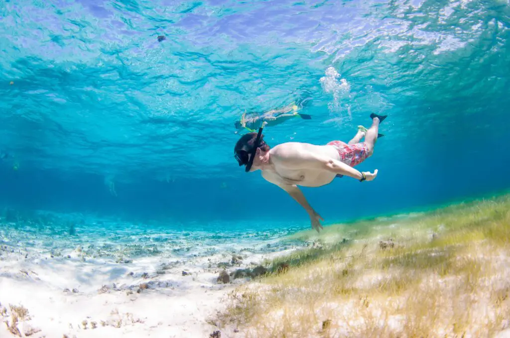 A man snorkeling in the clear waters off Grand Cayman with Red Sail Sports