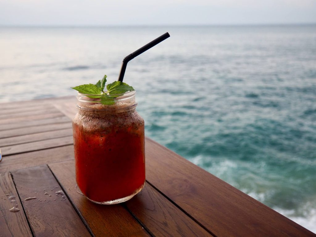 Red tropical summer cocktail on a wooden deck on the beach